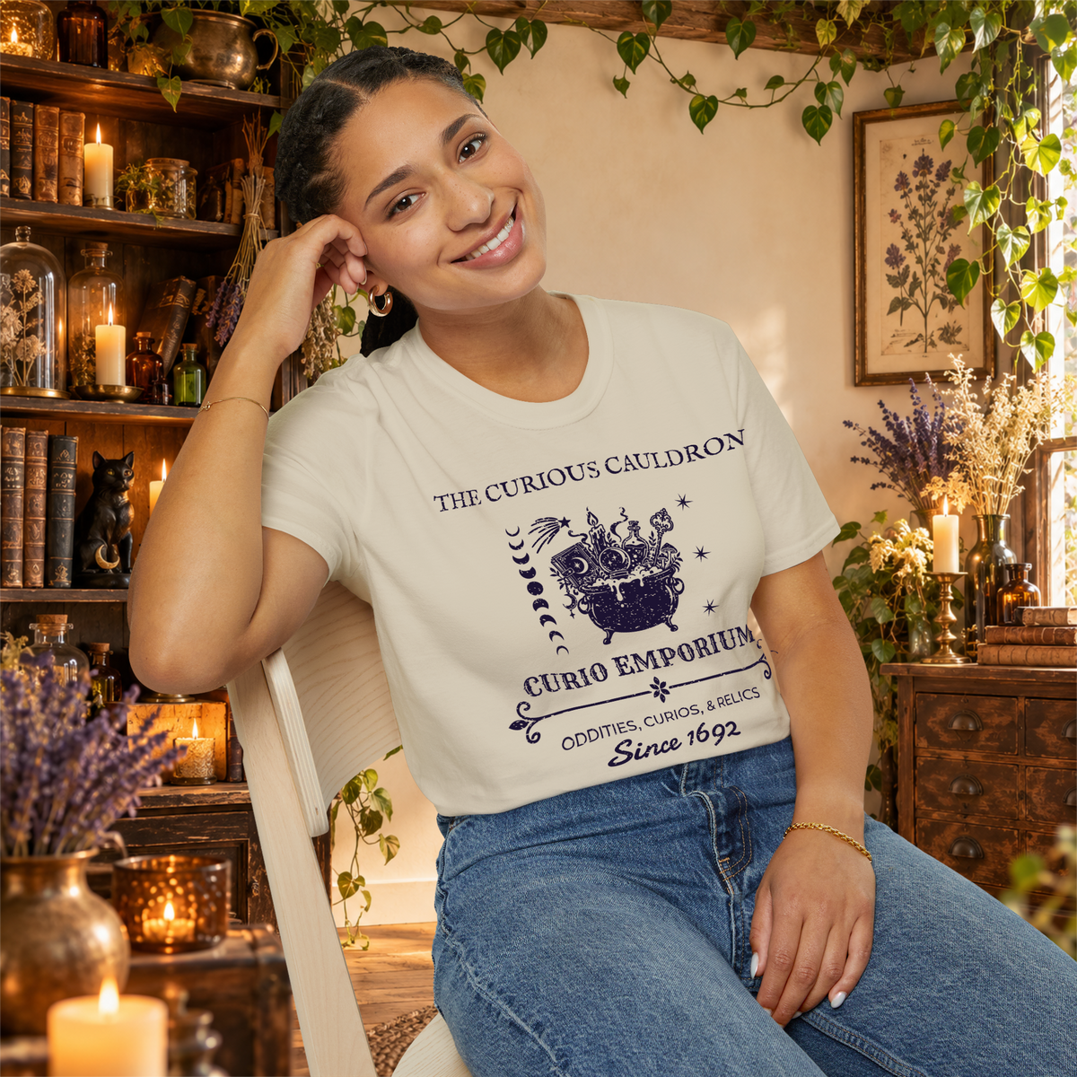 The Curious Cauldron graphic tee on seated woman