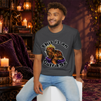 This Is an Outrage graphic T-shirt modeled by a seated man